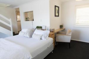 ein Schlafzimmer mit einem weißen Bett und einem Schreibtisch in der Unterkunft White Beach Cottage in Lake Cathie
