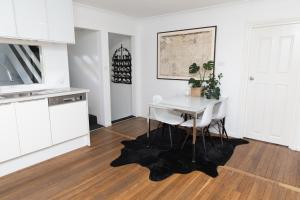 eine Küche mit weißen Schränken und einem Tisch und Stühlen in der Unterkunft White Beach Cottage in Lake Cathie + 13 Fotos