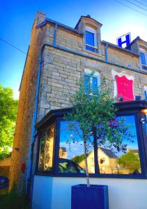 a building with a reflection of a tree in a window at Hôtel de Matignon Restaurant Le EmLo in Matignon