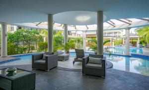 a poolside patio with chairs and tables and a swimming pool at Villasun Luxury Apartments & Villas in Flic-en-Flac