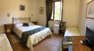 sypialnia z 2 łóżkami, biurkiem i telewizorem w obiekcie Villa Tuscany Siena w Sienie