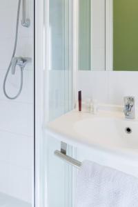 bagno con lavandino bianco e specchio di ibis budget Orange Centre a Orange