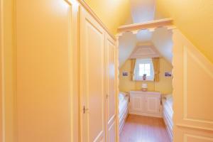 a yellow room with a bedroom with a bed and a window at Priel-Hüs in List
