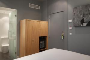 a bedroom with a wooden cabinet and a fireplace at Petit Palace Tres Cruces in Madrid