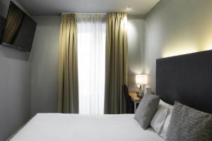 a hotel room with a bed and a window at Petit Palace Tres Cruces in Madrid