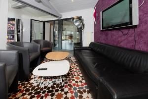 a living room with a couch and a tv on a wall at Motel D'ornex in Ornex