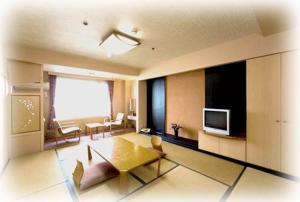 a living room with a table and a television at Aoshima Grand Hotel in Miyazaki