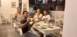 a group of people sitting around a table eating food at Boogie Hostel Kuta Lombok in Kuta Lombok