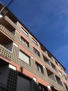 um edifício de tijolo alto com janelas brancas em Apartamento Turístico Puigcerdá Correos em Puigcerdà