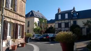 a street in a small town with parked cars at La P'tite Normande in Villerville
