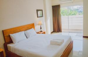 Schlafzimmer mit einem großen weißen Bett und einem Fenster in der Unterkunft Baan Kiang Wang in Phetchaburi