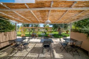 a patio with tables and chairs under a wooden pergola at Relais Tenuta Campì in Martano