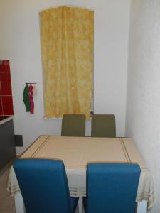 mesa de comedor con 2 sillas azules y ventana en Rajan Apartman, en Zagreb