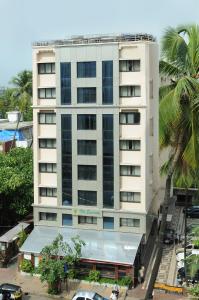 a tall white building with a palm tree in front of it at Regenta Place The Emerald in Mumbai