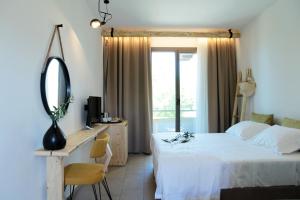 a bedroom with a bed and a desk and a mirror at Filippos Hotel in Skala Rachoniou