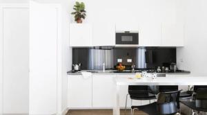 a kitchen with white cabinets and a table with chairs at App Leoncino Design Apartment in Rome in Rome