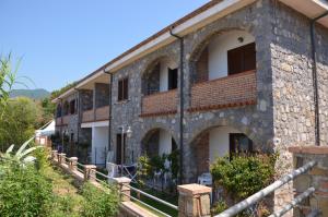 d'un vieux bâtiment en pierre entouré d'une clôture. dans l'établissement Residence Le Palme - Appartamenti sul mare - Spiaggia tra Palinuro e Caprioli, à Pisciotta