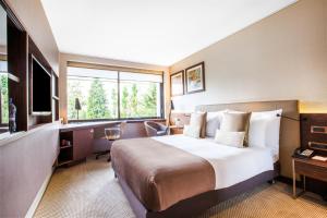 um quarto de hotel com uma cama grande e uma secretária em Crowne Plaza Geneva, an IHG Hotel em Genebra