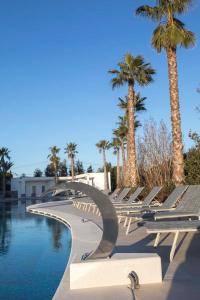 a swimming pool with lounge chairs and palm trees at Borgo San Barbato in Lavello