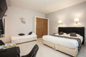 a hotel room with two beds and a chair at Hôtel Restaurant Plaisance-Piscine couverte et chauffée- Proche Sarlat- in Vitrac