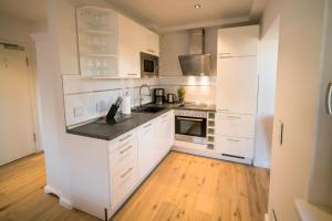 a kitchen with white cabinets and a wooden floor at Abendsonne in Westerland