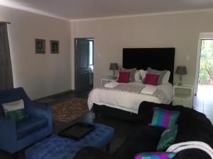 a bedroom with a bed and a couch and a chair at Bergvliet Cottages in Clarens