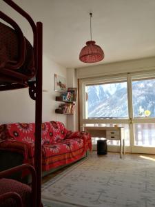 a living room with a red couch and a large window at L'Atelier du Temps - Appartamento CIRCE in Courmayeur
