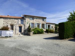 une maison en pierre avec une clôture blanche devant elle dans l'établissement La Roseraie à 10min du Puy du fou, à Saint-Mars-la-Réorthe