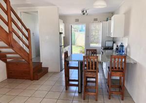 a kitchen with a table and chairs and a staircase at 26 Settler Sands Beachfront Accommodation Sea View in Port Alfred