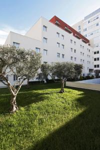 duas árvores na relva em frente a um edifício em Aparthotel Adagio Access Marseille Prado Périer em Marselha