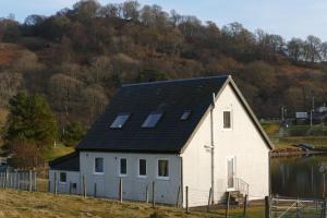 una casa blanca con techo negro en una colina en Wallace Lodge en Crieff
