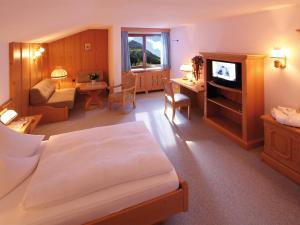 a bedroom with a bed and a living room with a television at Hotel Omesberg in Lech am Arlberg