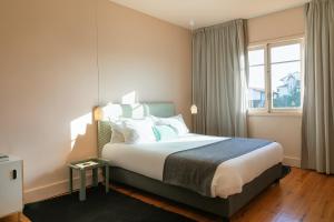 a hotel room with a large bed with a window at Slowly Garden House in Porto