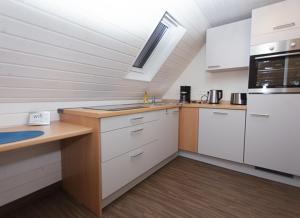 a kitchen with white cabinets and a counter top at Haus am Asang in Löwenstein +4 photos