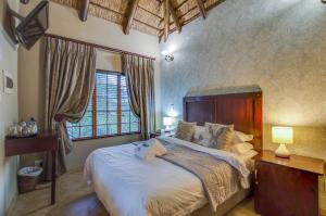 een slaapkamer met een groot bed en een groot raam bij Kassaboera Lodge in Hartbeespoort