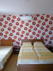 two beds in a room with red flowers on the wall at Bolyarski Stan Guest House in Veliki Preslav