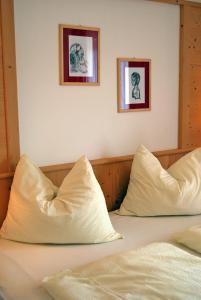 a bed with two pillows and two pictures on the wall at Gasthof Weidmannshof in Bressanone