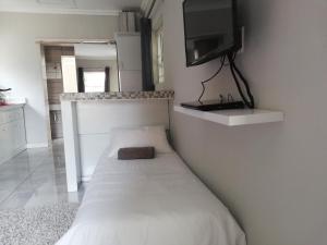 a bedroom with a bed with a tv on the wall at Feet Up Cottage in Somerset West