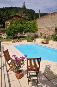 a swimming pool with two chairs and purple flowers next to it at Les Jardins de l'Hacienda in Tarare