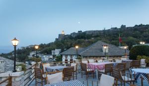 a restaurant with tables and chairs on a balcony at Hotel Kodra in Gjirokastër