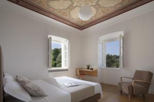 a bedroom with a bed and a chair and two windows at Villa Orti in Dubrovnik