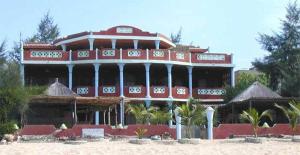 un grande edificio sulla spiaggia con palme di A Keurmaya a Saly Portudal