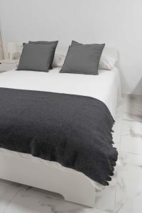 - un lit blanc avec une couverture noire dans l'établissement Céntrico Apartamento cerca de la PLAYA, à Puerto de la Cruz