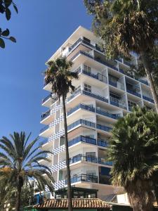 a tall white building with palm trees in front of it at Skol Apartments Marbella in Marbella