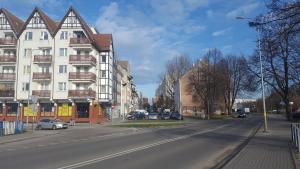 a city street with a building and cars on the road at Szafir Apartament in Kołobrzeg