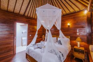 a bedroom with a bed with white mosquito netting at Lembongan Small Heaven Bungalow in Nusa Lembongan