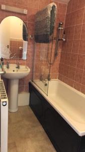 uma casa de banho com um lavatório, uma banheira e um espelho. em Kinder Lodge em Hayfield