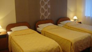 zwei Betten in einem Hotelzimmer mit gelber Bettwäsche in der Unterkunft Hotel Rydzewski in Lyck + 35 Fotos
