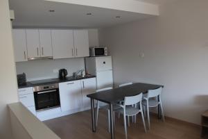 a kitchen with white cabinets and a black table and chairs at Le Pré-Chet in Profondeville