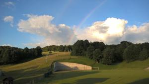 a rainbow in the sky over a green field at Guesthouse Bor Plitvice Lakes in Plitvička Jezera